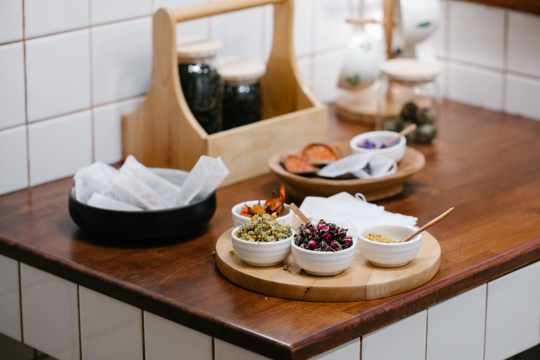 Bowls of dried herbs and botanical ingredients on a wooden worktop