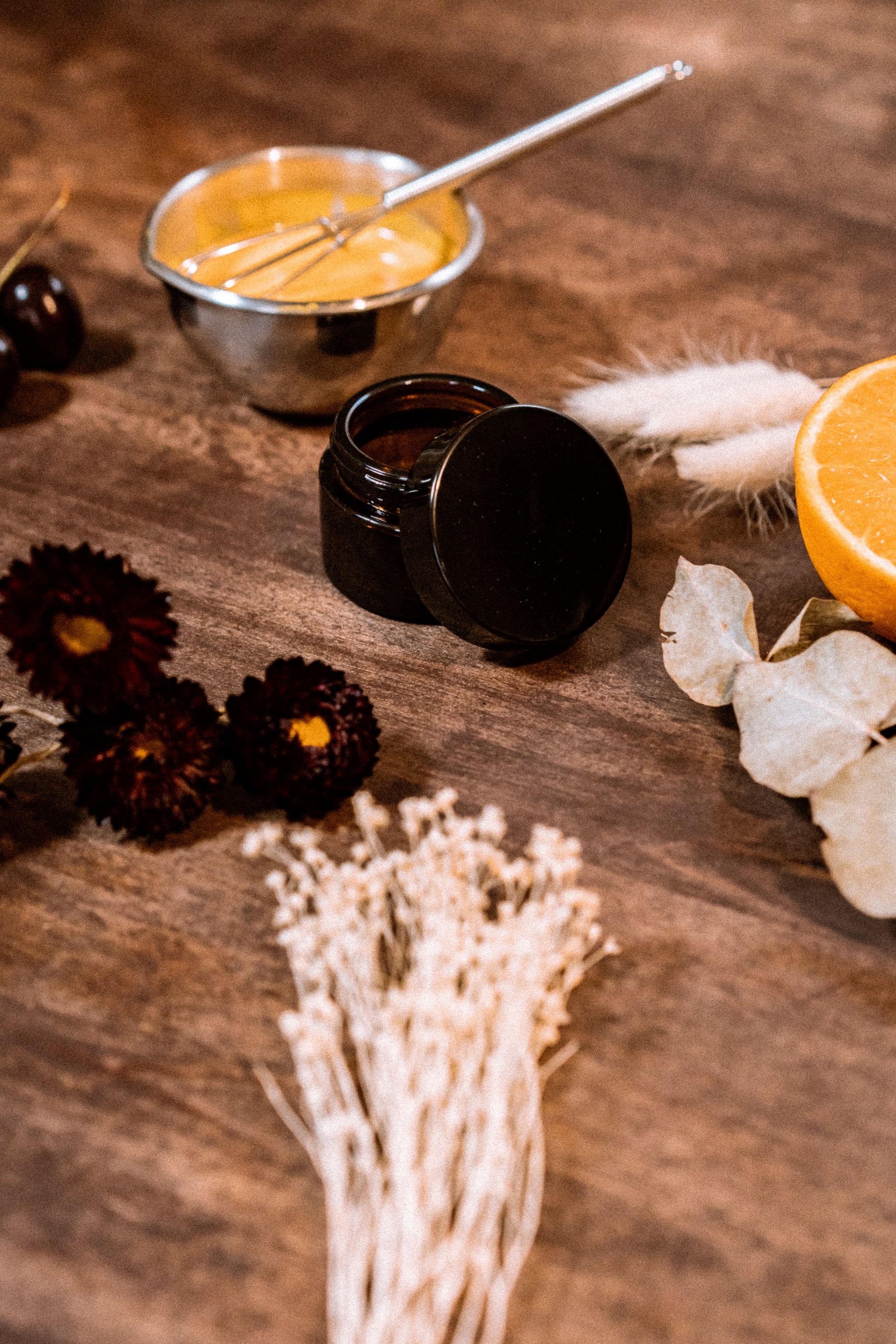 Natural cosmetic ingredients, jars, and dried botanicals arranged on a worktop